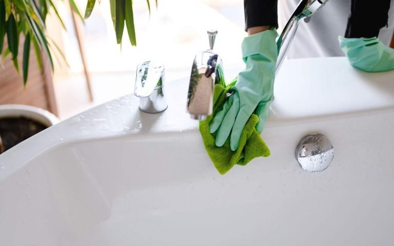 Bathtub cleaning with gloves and scrubber, ensuring hygienic and spotless results.